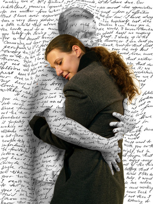 A woman hugging another person with writing on the wall behind her.