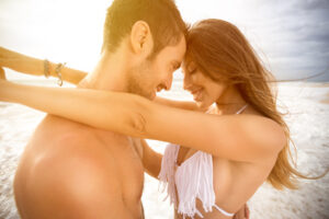 A man and woman embracing each other on the beach.